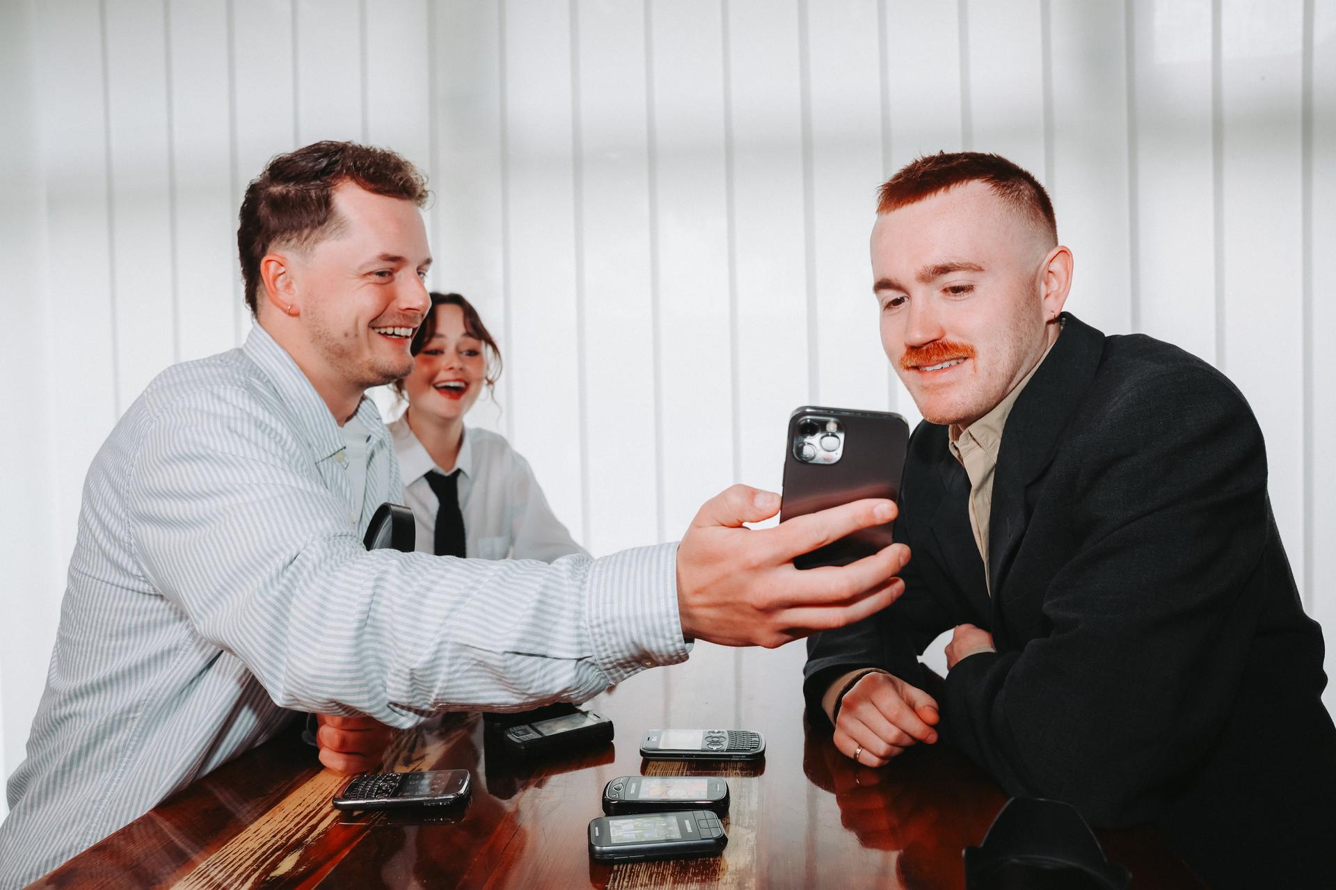 Three SocialFind colleagues looking at a phone together
