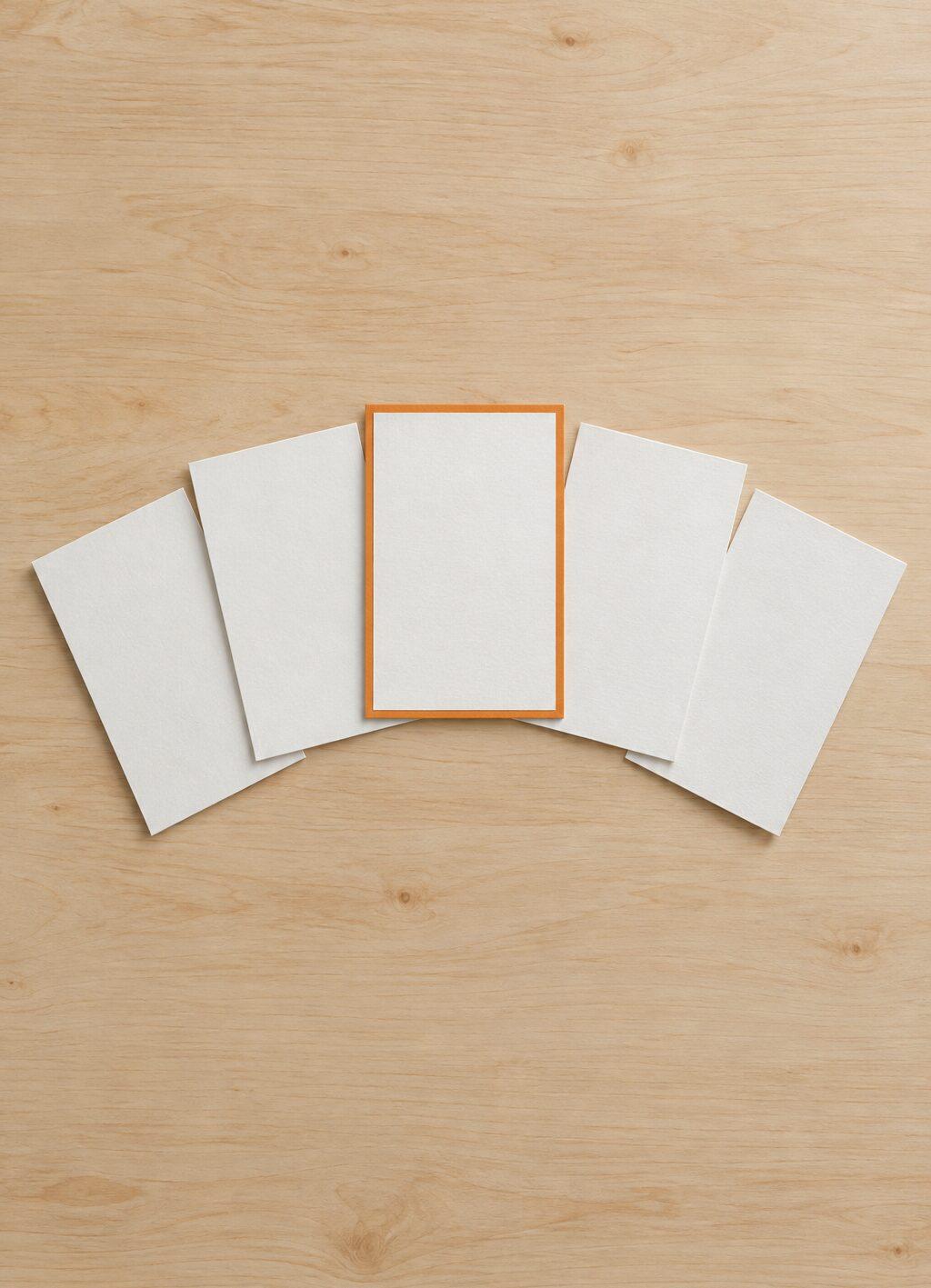 Vijf witte kaarten waaiervormig uitgelegd, de middelste met een oranje rand.